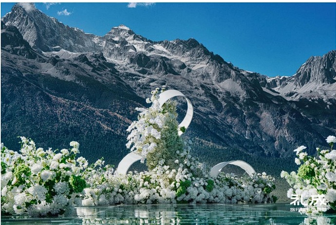 A white floral wedding installation on the turquoise glacial water of Blue Moon Valley beneath the snow peaks